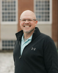 white male with glasses smiling