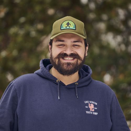 Male with facial hair, a navy hoodie, and an army green ballcap
