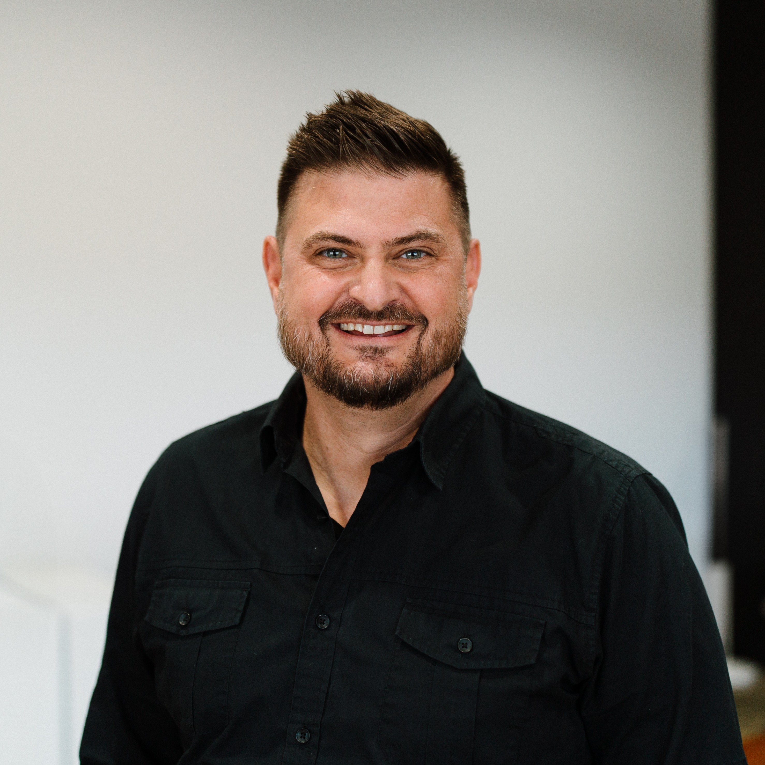 white male in dark collared shirt smiling