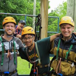 group of young adult men wearing yellow helmets and harnesses
