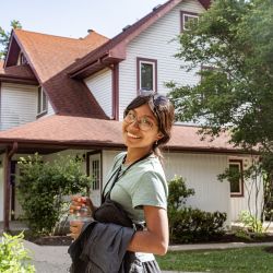 young adult female in looking back over her shoulder outside in front of a white and red building