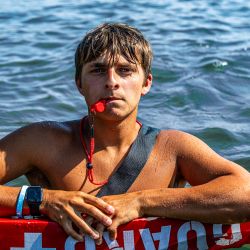 young man with red whistle and serious face while in water