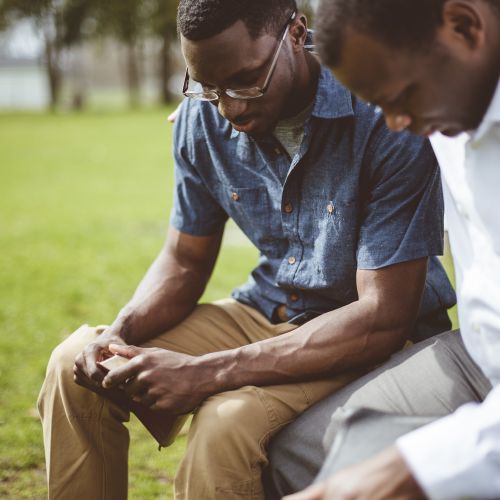 Two African-American men praying together.
