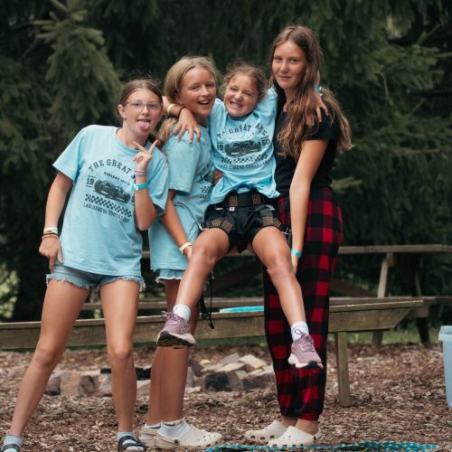 Jr High Students smiling by the zipline at camp