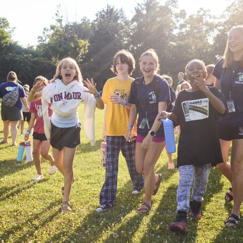 kids and cabin leaders walking towards the camera laughing with the sun.
