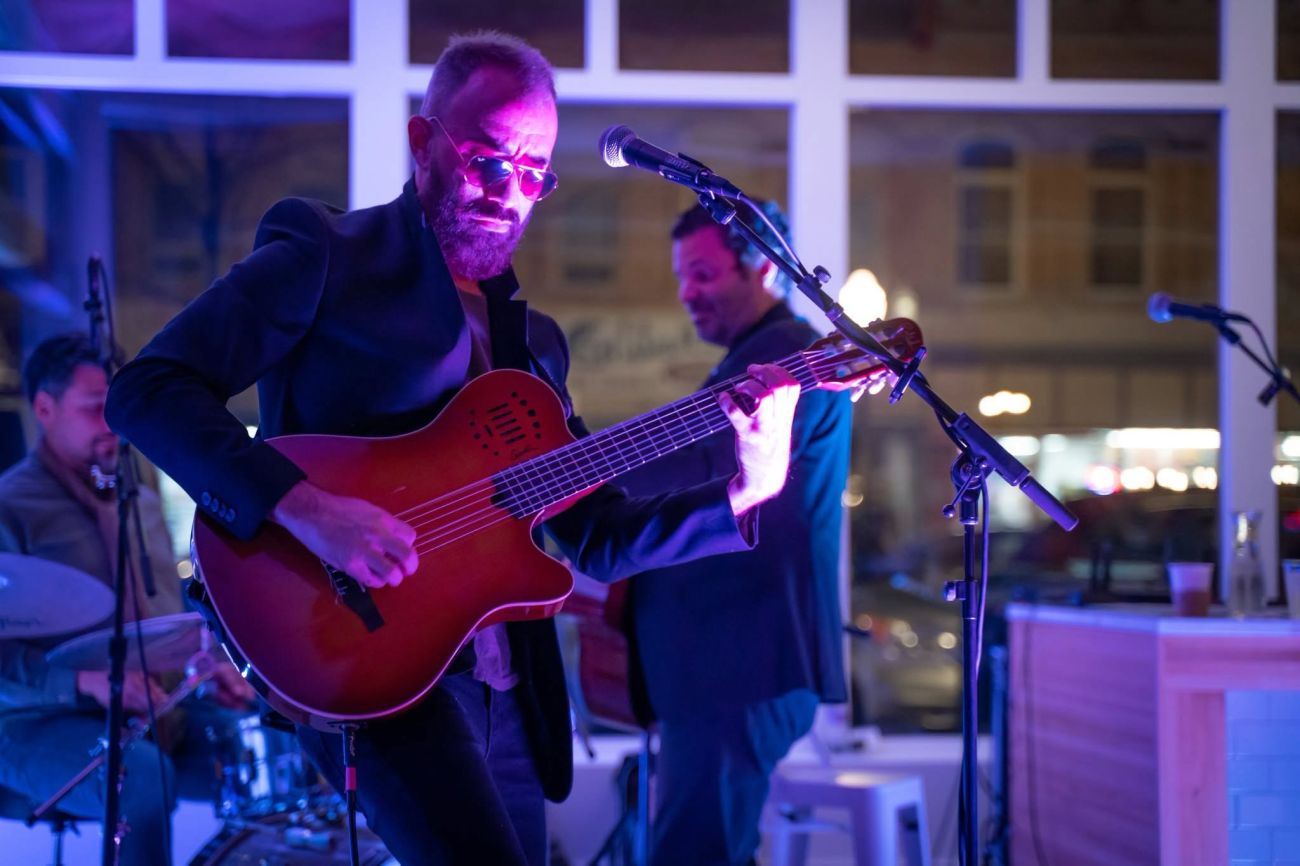 Man with sunglasses playing a guitar at a banquet or gala