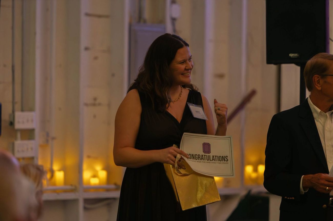 A woman showing enthusiasm as she holds a piece of paper that reads "Congratulations"