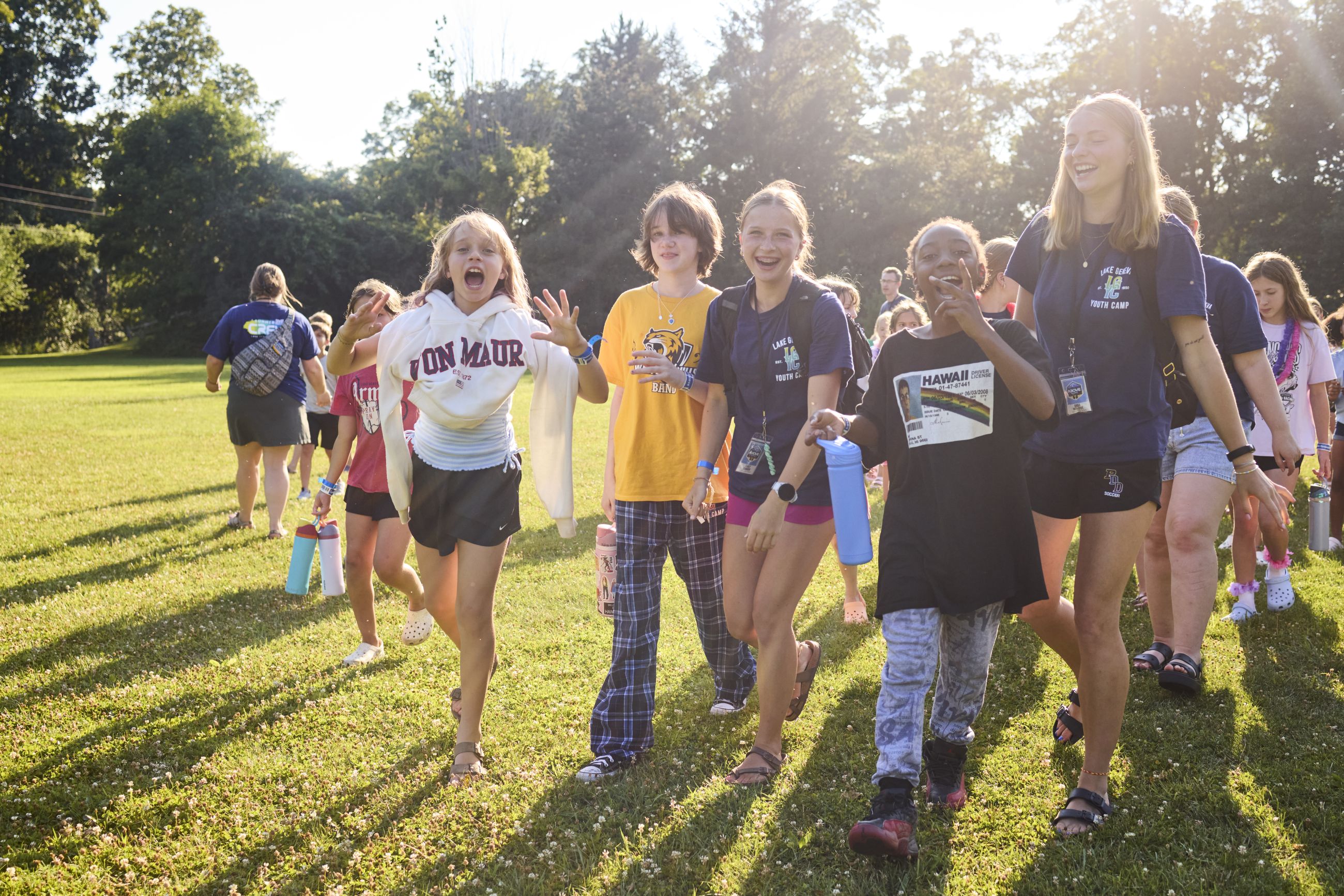 kids and cabin leaders walking towards the camera laughing with the sun.